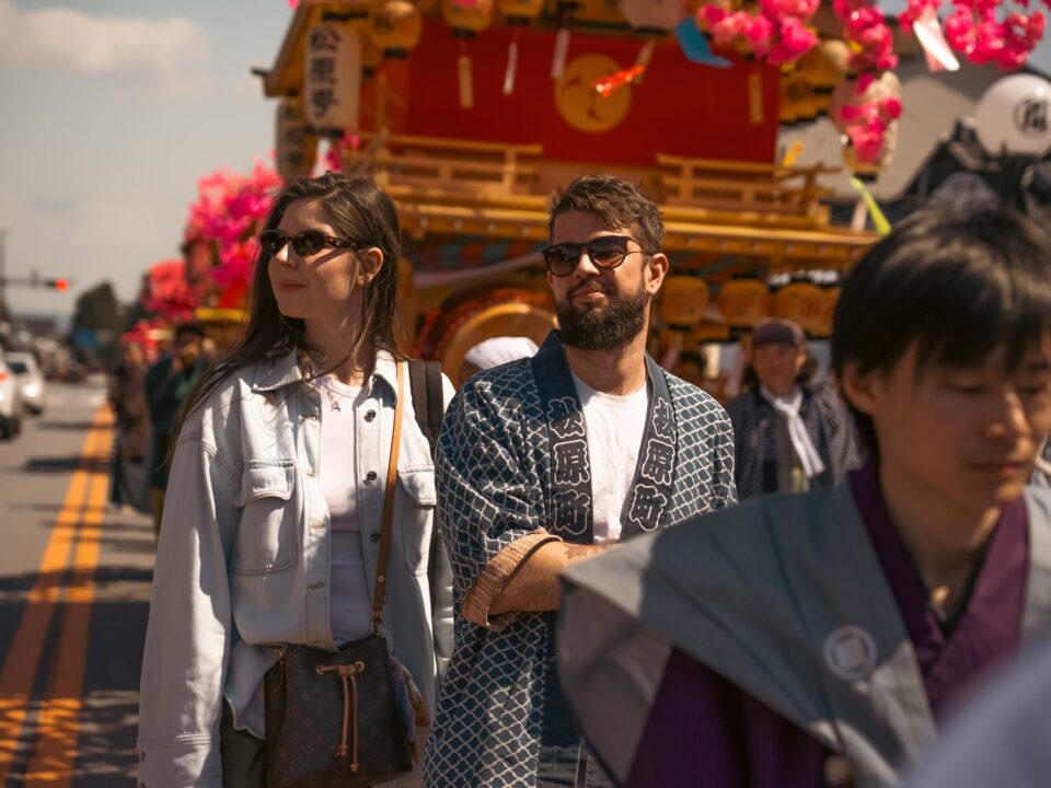 日光の祭りで、山車の前を歩くツアーのゲストと地元の人